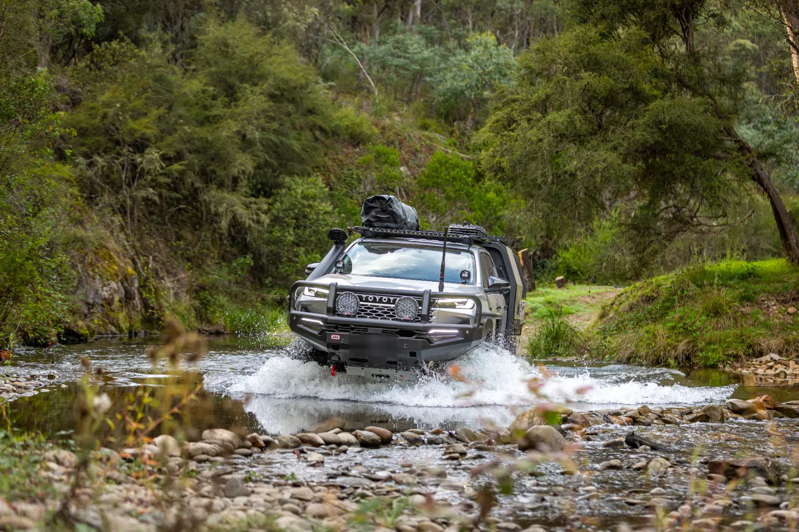 Toyota Hilux with ARB bar crossing a river on a forest track
